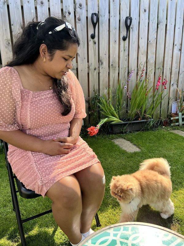 Rosemerry in a pink dress sitting in a garden with a fluffy dog